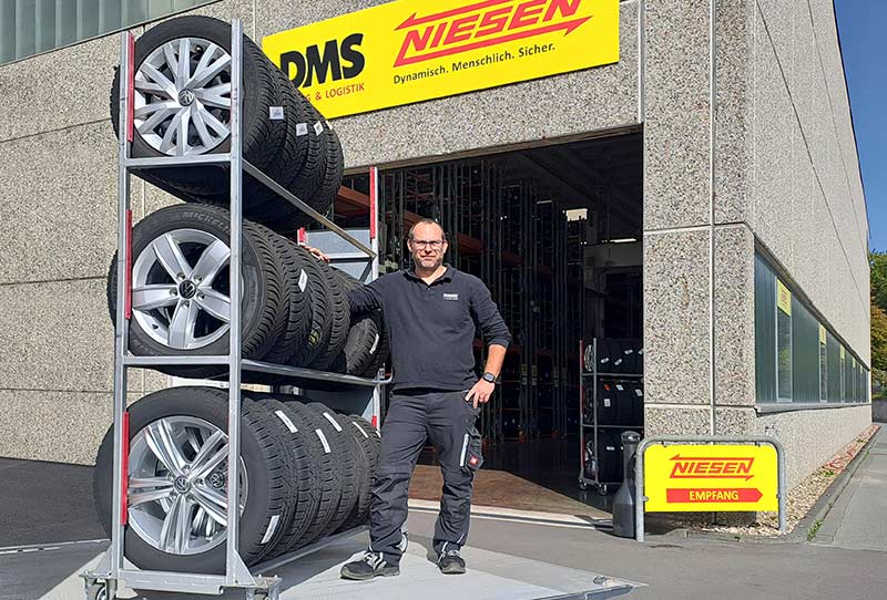 Mitarbeiter auf LKW-Laderampe mit Räder-Transportwagen