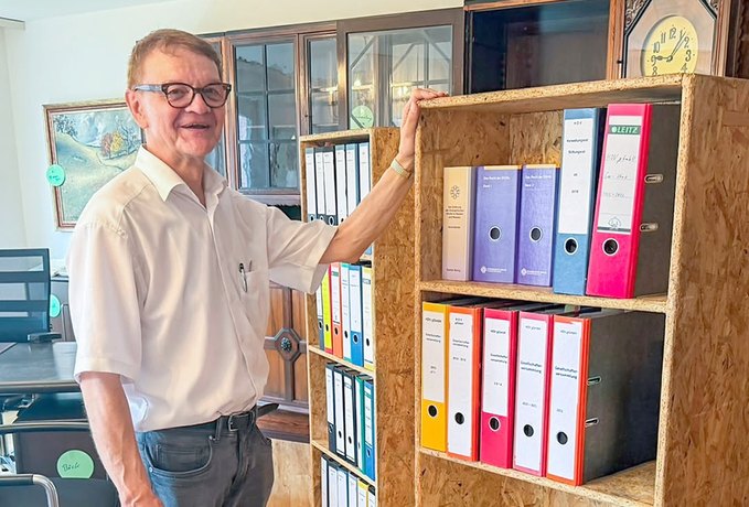 Dr. Martin Zentgraf, Vorstand des Hessischen Diakonievereins, neben der Schrankwand