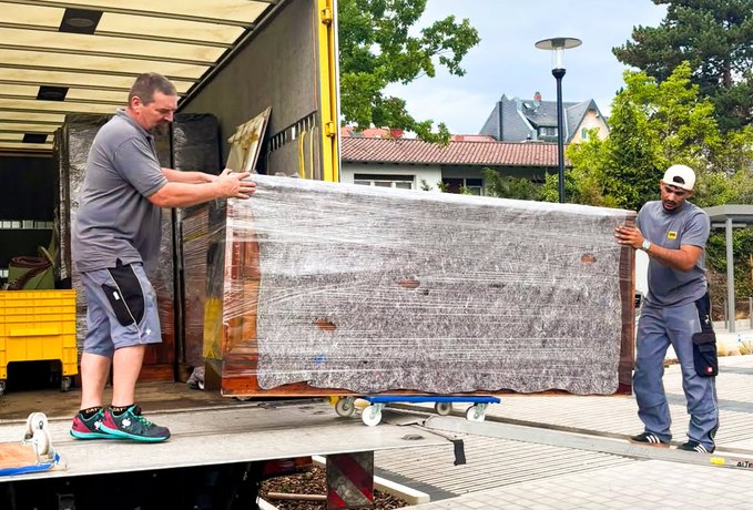 Umzugsprofis von DMS Friedrich Friedrich verladen die in Folie gepackte Schrankwand