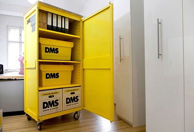 Gelber DMS-Aktenrollwagen mit Umzugskartons im Büro
